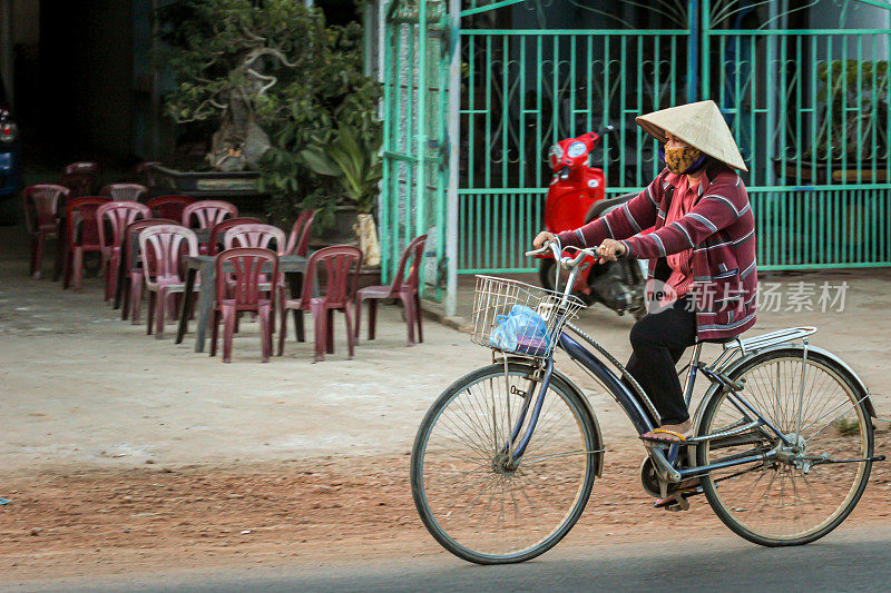 当地成年越南人带着货物骑着自行车在路上行驶。