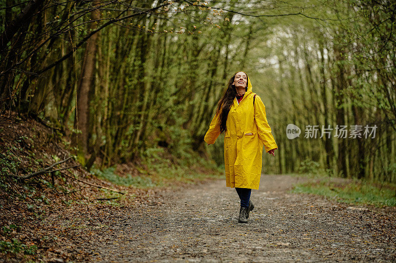 雨中穿着黄色雨衣的年轻女子