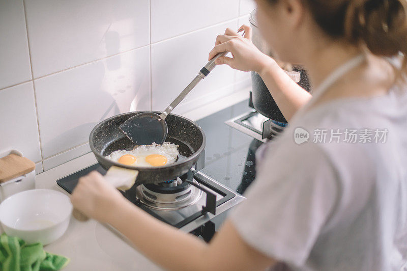 一位亚洲的中国美女正在厨房里煎鸡蛋准备吃早餐