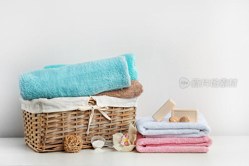 柳条洗衣篮里有毛巾，洗涤剂，肥皂和竹球在白色的背景