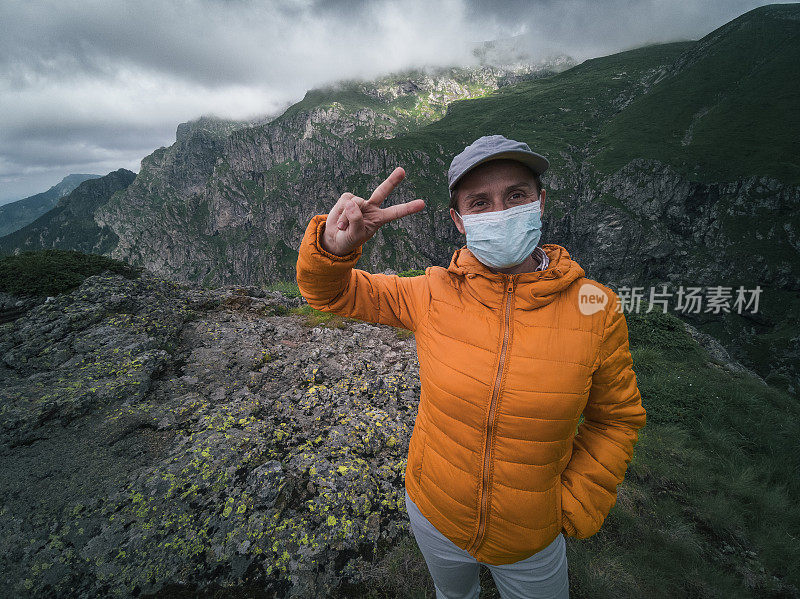 回归自然。新的标准。一个女人独自旅行者的肖像与保护性面具在她的脸上徒步在山上。2019冠状病毒病大流行期间，阳光明媚的户外享受。