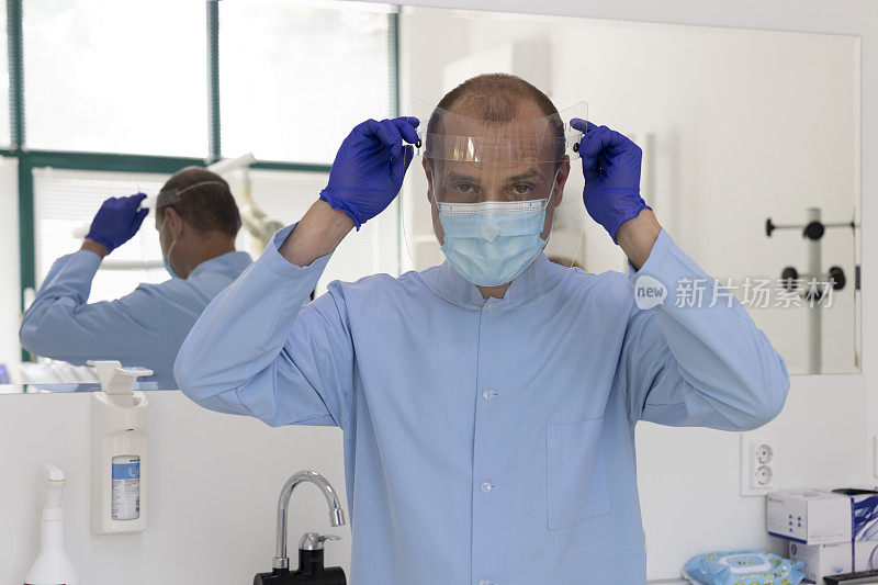 牙科医生戴着防护面罩准备检查的牙医在大流行期间工作。