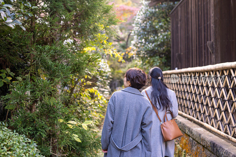 日本女性朋友走在狭窄的小路上的后视图