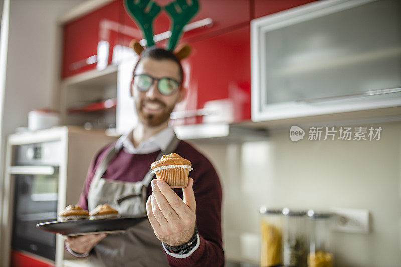 一个年轻人正在家里的厨房里准备圣诞晚餐。他正在准备松饼作甜点