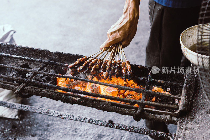 人们在燃烧的木炭上烤鸡肉