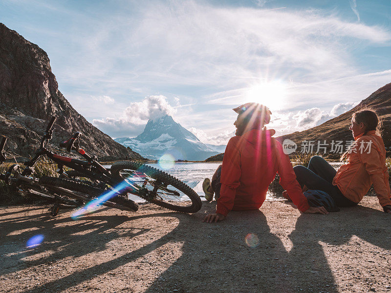 几个山地自行车手在湖边放松，凝视着日落时的马特洪山