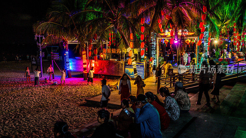 三亚夜生活与酒吧入口的人在大东海海滩晚上在中国海南岛三亚市