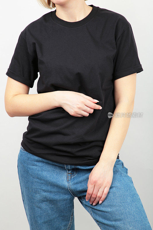 灰色背景下穿着黑色t恤的年轻女孩。t恤设计和人的概念-近距离。