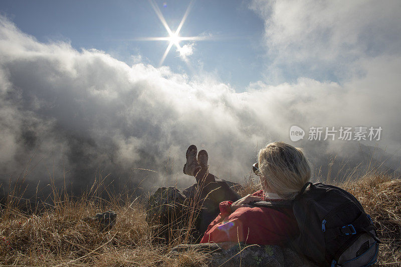 女徒步旅行者在阳光明媚的山脊上放松