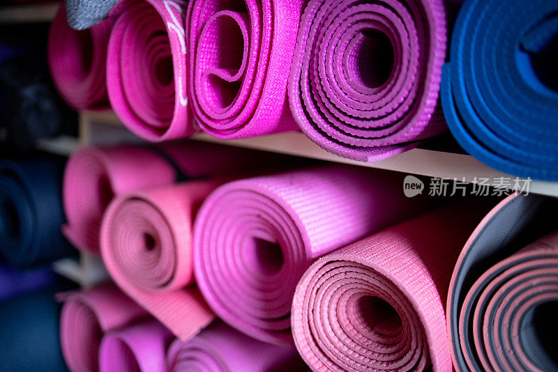 健身房储藏室架子上的粉色和紫色瑜伽垫