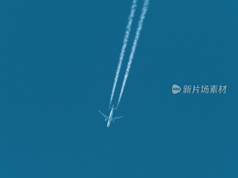 飞机在蓝色的天空中飞行，后面拖着白色的水雾