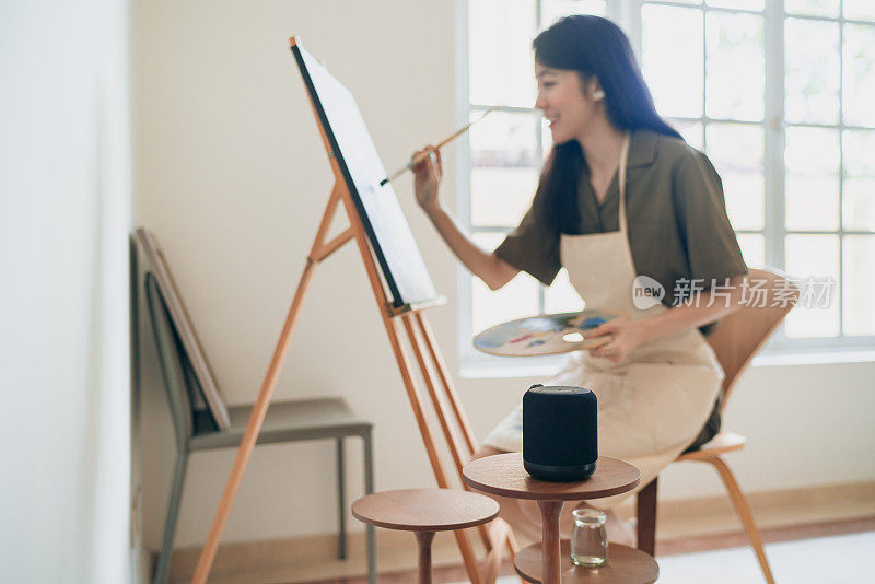 虚拟辅助家庭-女性画家绘画与智能扬声器在她的身边，以方便