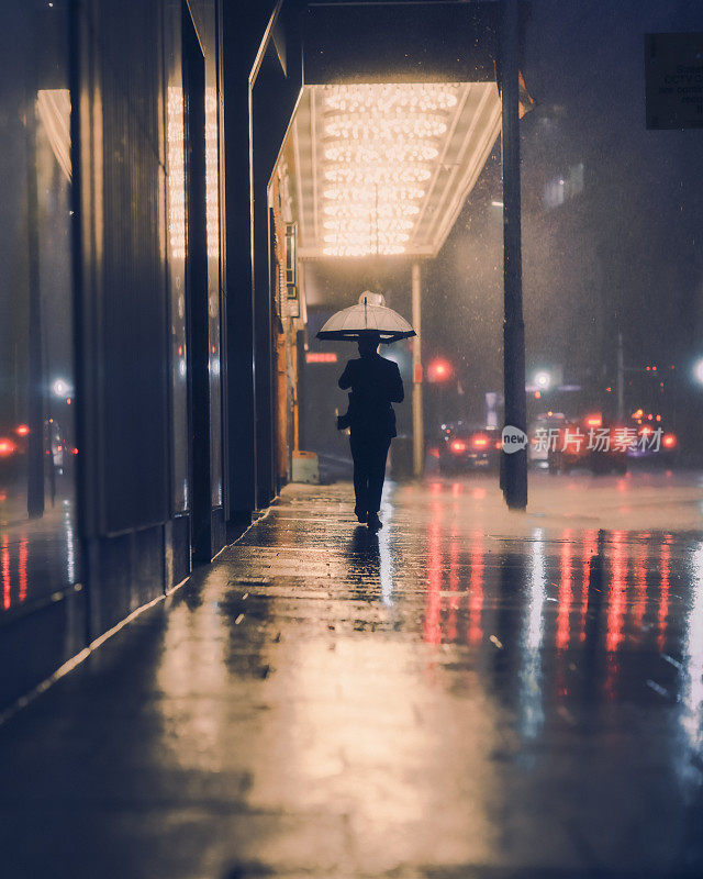 带着雨伞独自在雨中行走的人。城市街道-空无一人