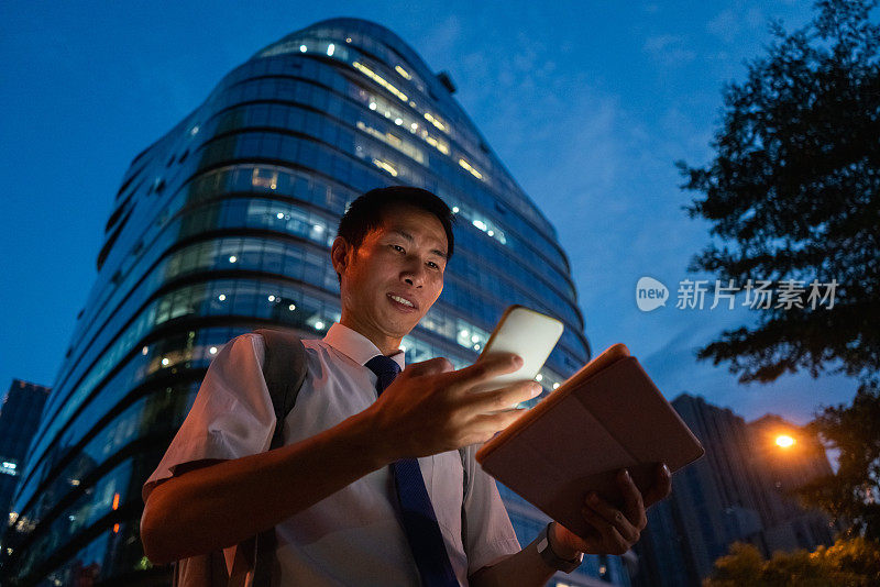 一名亚洲白领在香港中央商务区的大楼之间使用智能手机