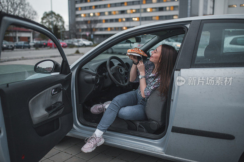 一个饿女人在停车场吃披萨