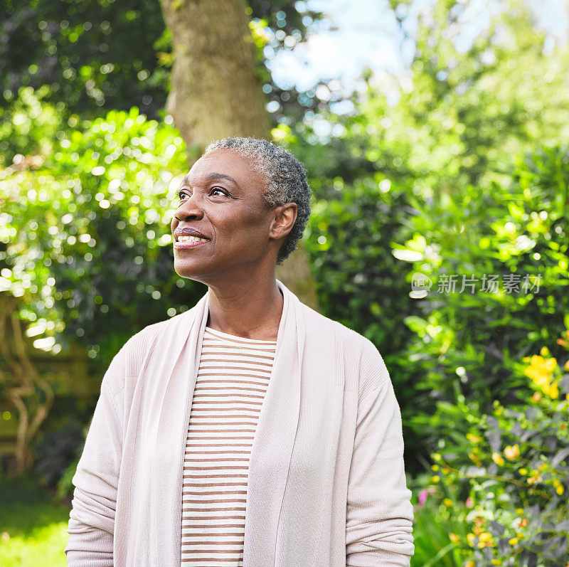 一个自信成熟的女人快乐地站在花园里思考。一位老妇人在外面悠闲地思考着
