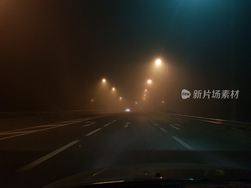 在大雾弥漫的夜晚，希腊埃格纳蒂亚大街上的道路车辆亮起了灯