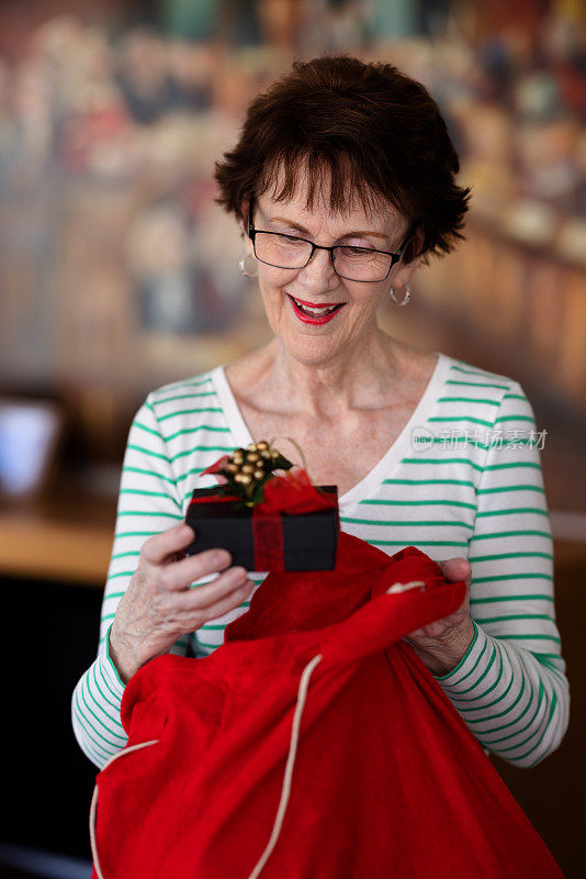 一个年长的女人从一个红色的袋子里拿礼物