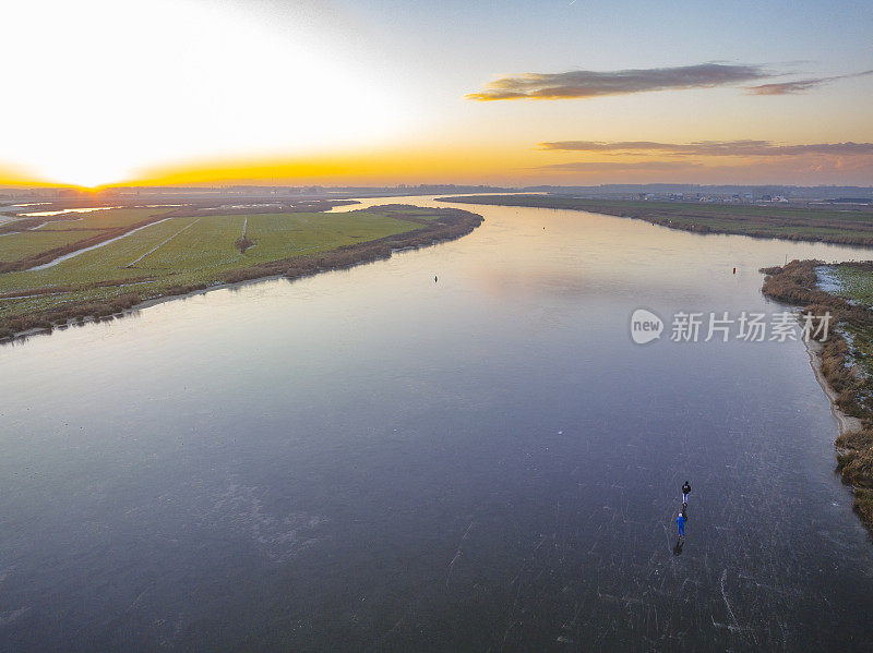 在美丽的冬日夕阳下，荷兰的湖面上滑冰