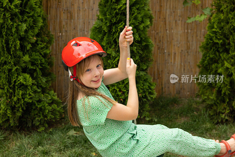 年轻的白人女孩戴着安全帽荡秋千