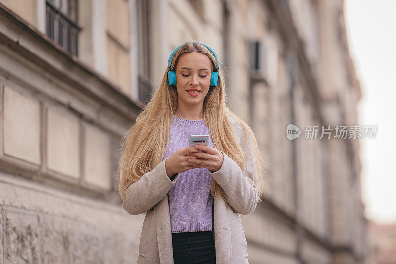 年轻自信的女人在街上听音乐的肖像