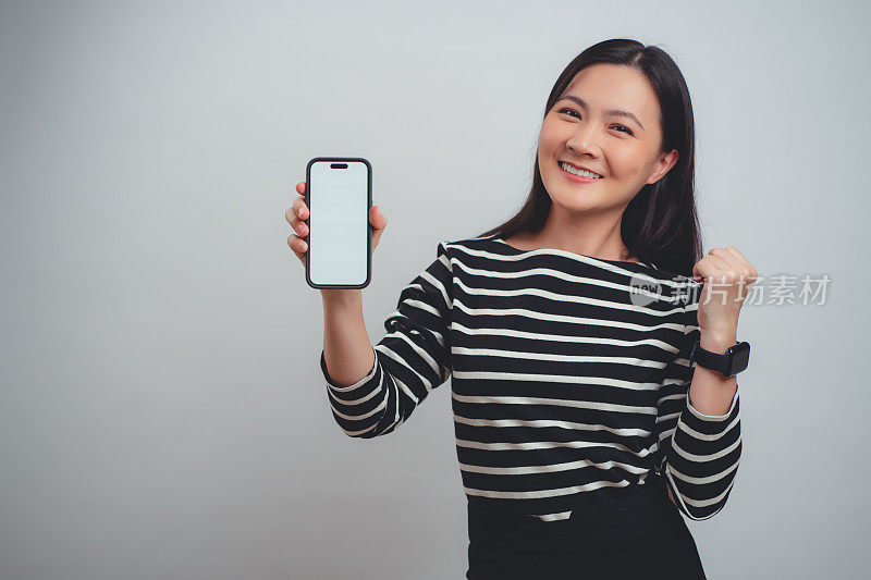一名亚洲女性开心地笑着，智能手机上的白色屏幕孤立地站在白色背景上。
