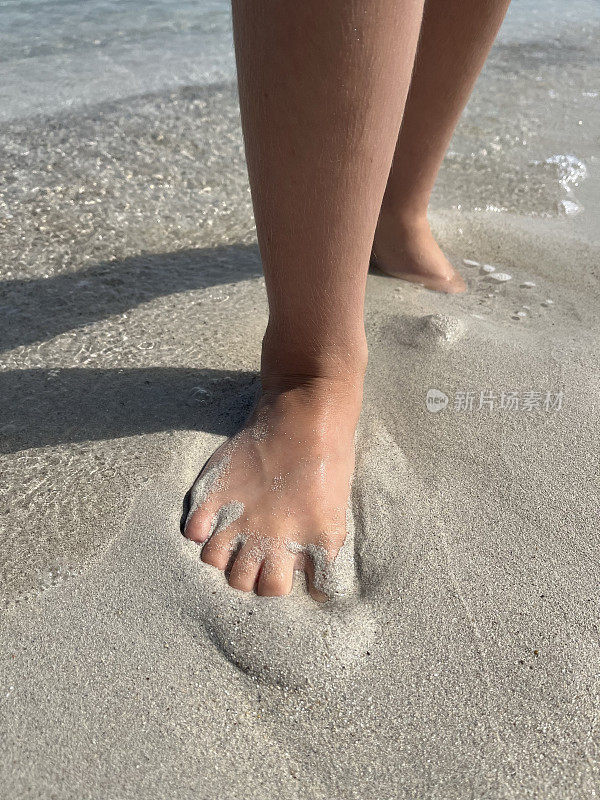 孩子的脚踩在沙滩上