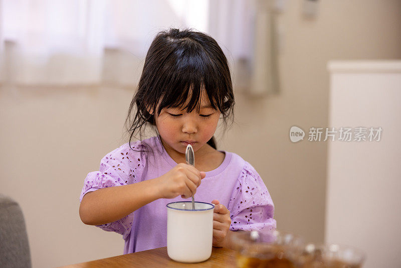 小女孩正在用勺子搅拌一杯牛奶