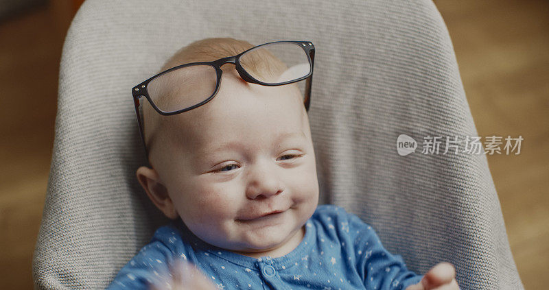 快乐的男婴戴着眼镜，在家里的保镖上放松