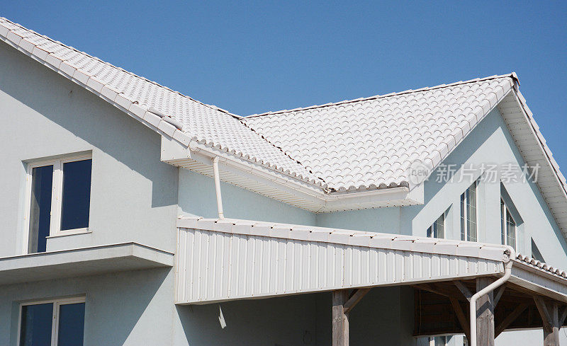 白色瓦片屋顶的房子，有雨沟管道，斜檐和问题区域的防水。屋面施工。