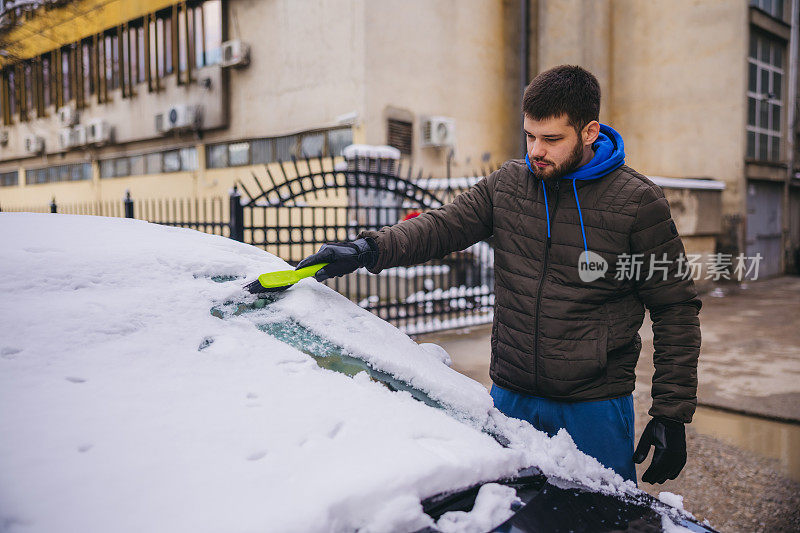 年轻人正在清除汽车上的积雪