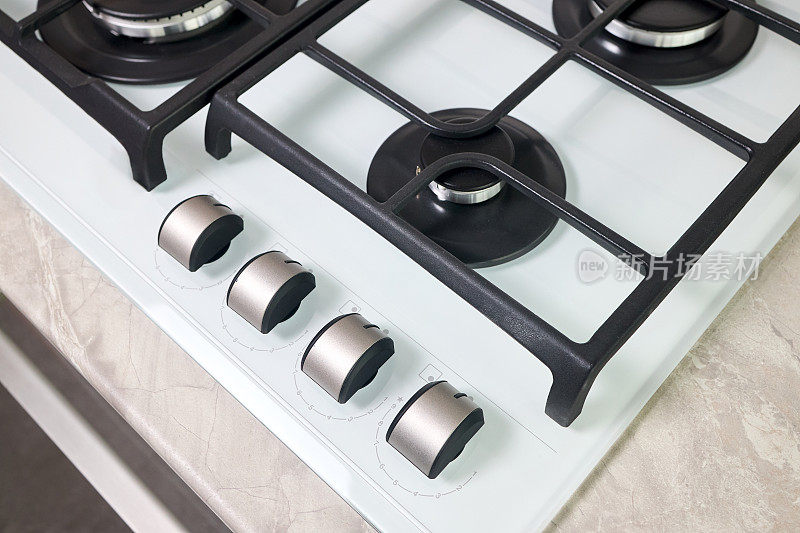 炉具炉具烤箱由白色玻璃烤架不锈钢控制旋钮选择性聚焦在失焦烤箱燃烧器在台面陶瓷石器背景制成。