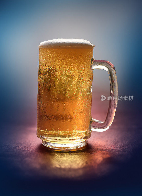 啤酒在玻璃啤酒杯的图像覆盖在凝结与起泡的气泡形成泡沫的啤酒，背光马克杯品脱玻璃，重点在前景上