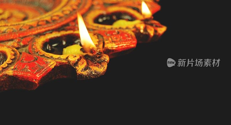 水平照片的印度节日排灯节Deepawali被庆祝点燃两个灯柱的Diya灯和庆祝与明亮的彩色赤陶土灯在黑色的背景
