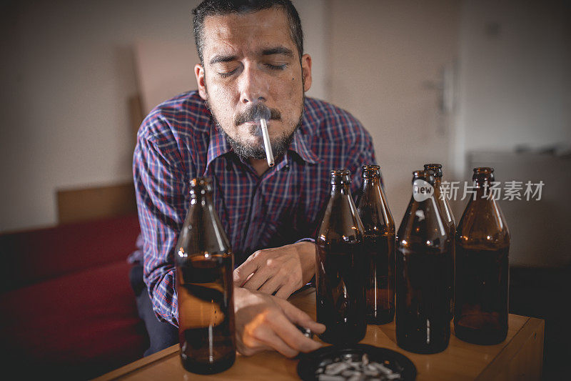 年轻悲伤的醉酒男子喝啤酒和酒精感到浪费，孤独和绝望的痛苦和情绪压力。人与酗酒、上瘾和男人抑郁的概念。