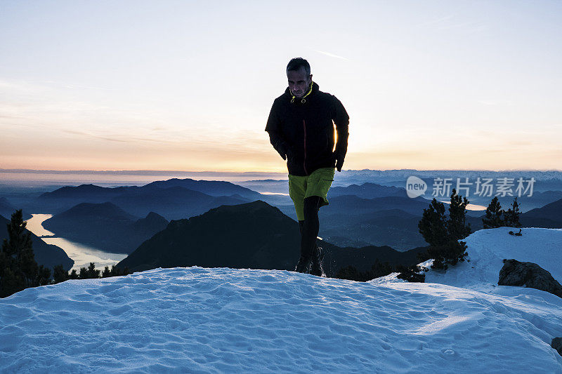 黎明时分，一名徒步运动员爬上雪山的山脊