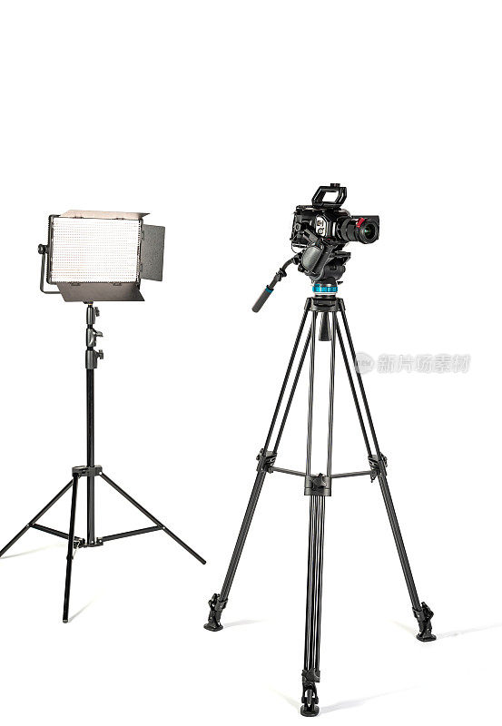 专业的视频电影摄像机在相机三脚架和专业的照明灯具在白色工作室背景