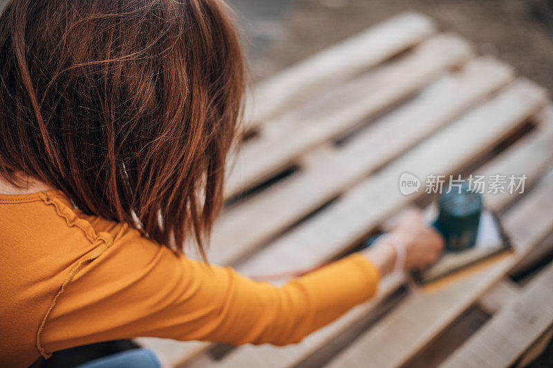 忙碌的DIY妇女在建筑工地上刮木板