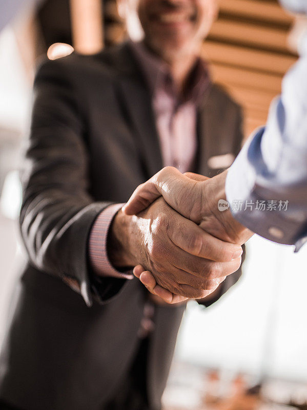 企业家在办公室握手的特写。