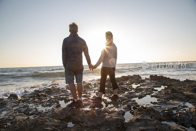一对成熟的夫妇在日出时探索潮滩