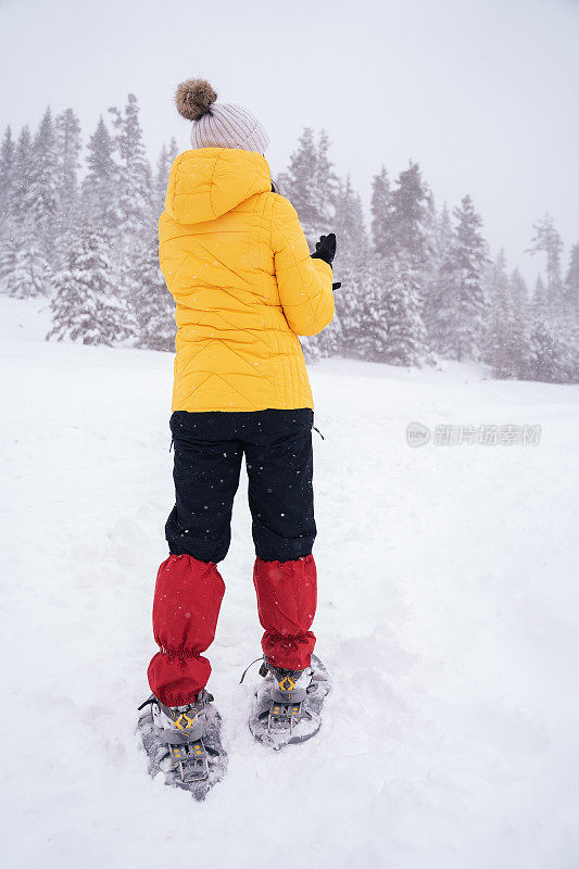 冬天的旅行者。年轻的女游客走在深深的雪中，享受冬天的山。肖像。