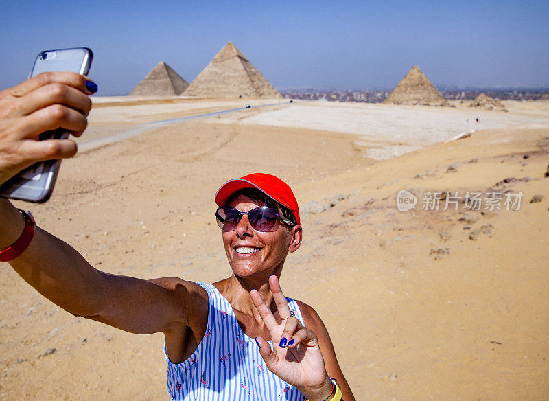 微笑的成年女子以吉萨金字塔为背景自拍