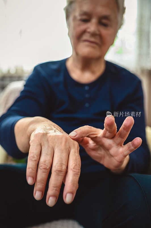 老年妇女揉着她患有风湿病的手腕和手臂