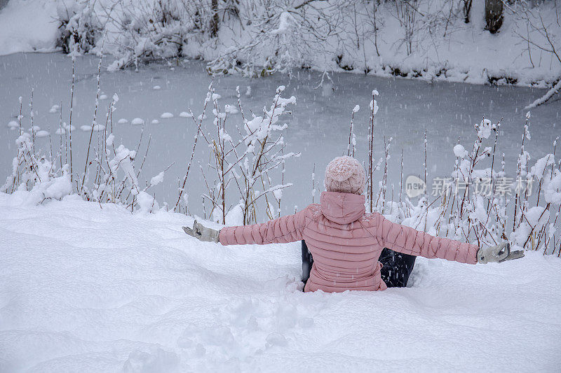 女徒步旅行者在白雪覆盖的河岸放松