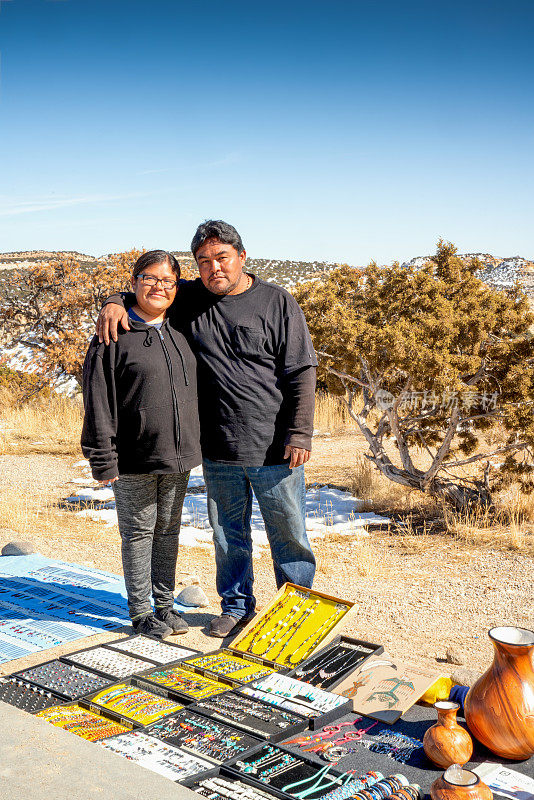 在犹他州沙漠的路边小摊上，一对年轻的纳瓦霍夫妇向顾客出售正宗的陶器和珠宝