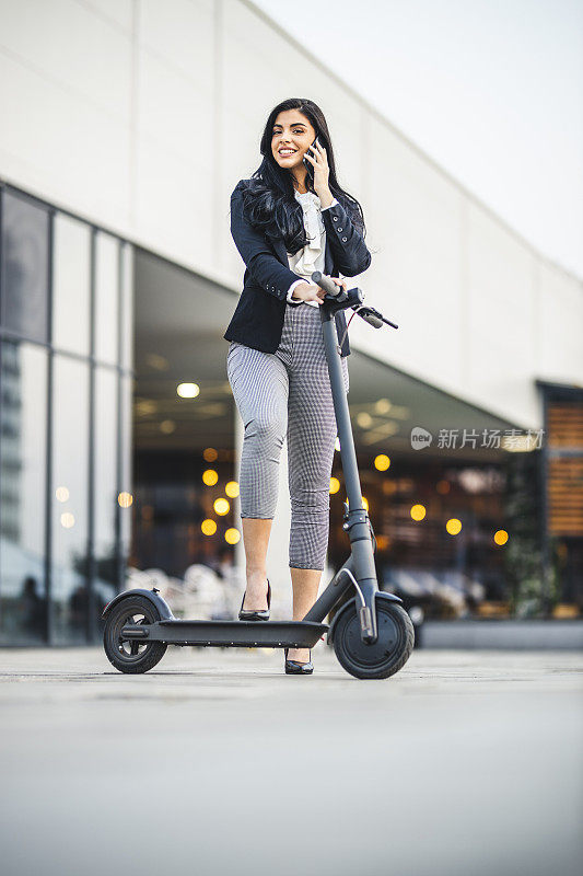 在城市里使用智能手机和骑摩托车的女商人