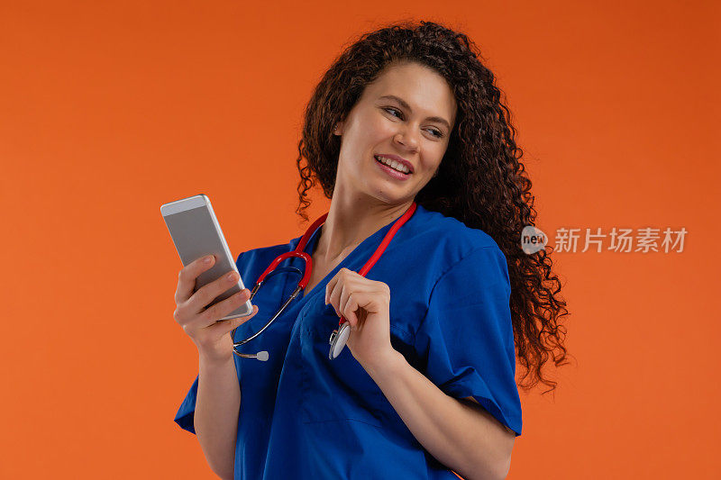 年轻女医生，带着智能手机，橙色背景