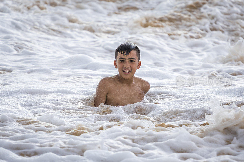 少年在海浪中嬉戏。