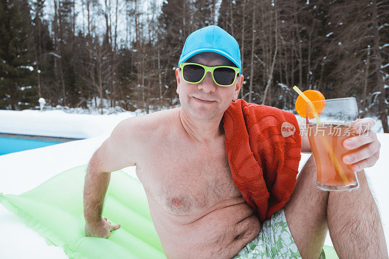 一名男子穿着泳裤，戴着墨镜，躺在游泳池附近的一个充气床垫上。一个男人用吸管喝果汁。寒假在家。周末在别墅。