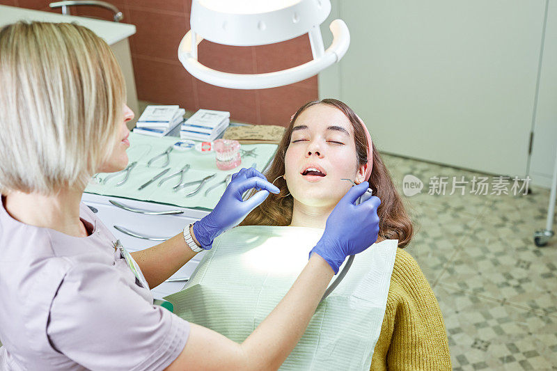 一个年轻的女人坐在牙科诊所的牙科椅上。医生和女病人。